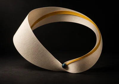An ivory ribbon forms an open loop with a gold inner stripe and a small teal connector.